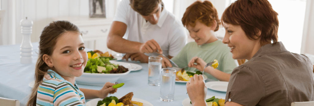 Une photo en couleur d'une famille assise en train de manger.