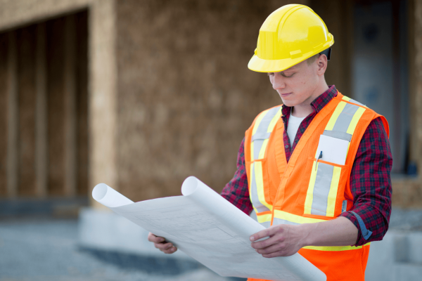 'un jeune homme avec un casque dur jaune qui regarde un plan